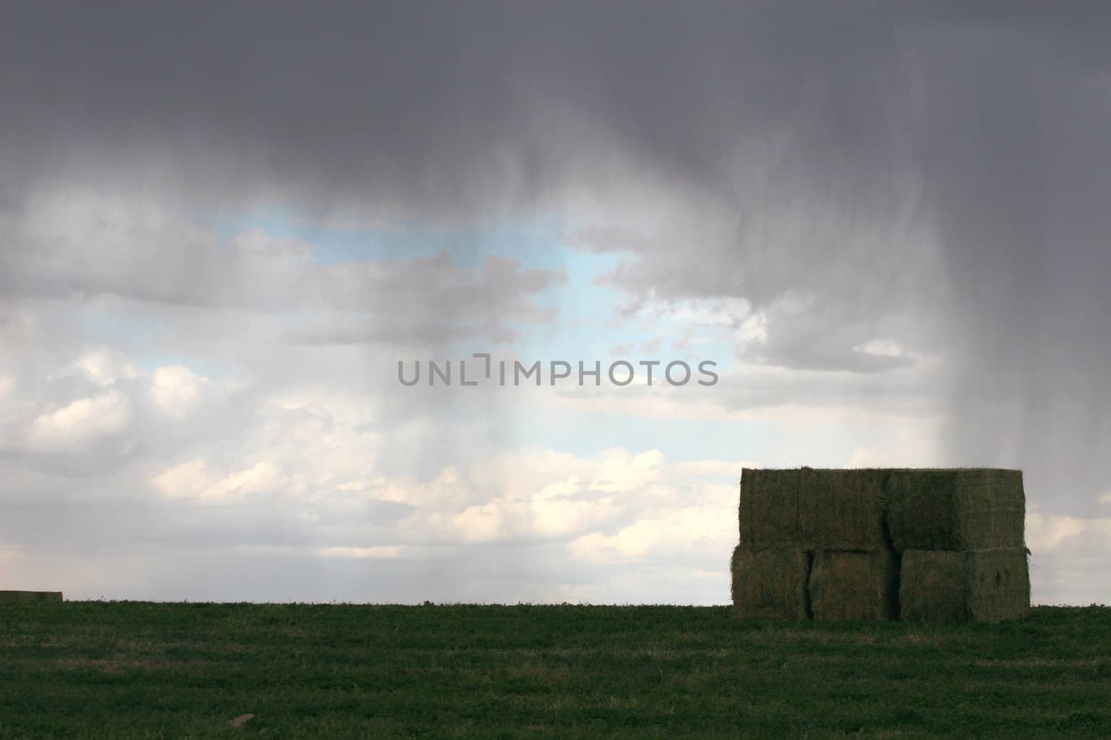 Begingings of rain over freshly baled hay field