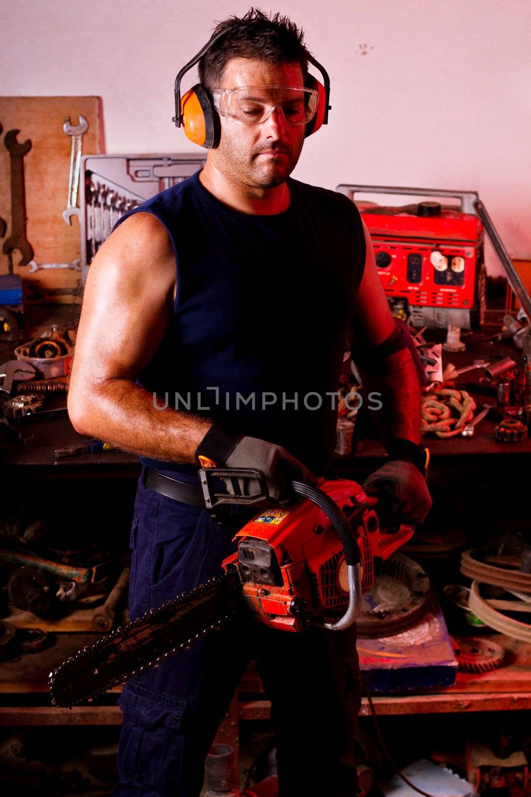 View of a garage mechanic man holding a chainsaw.