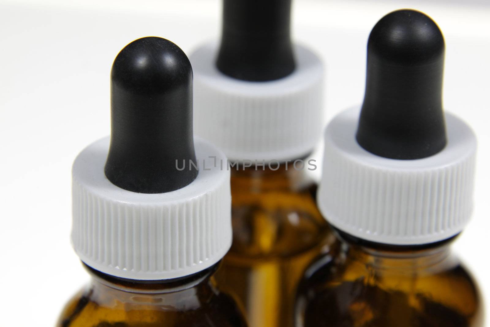 Three dropper bottles containing naturopathic medicine, isolated on a white background.
