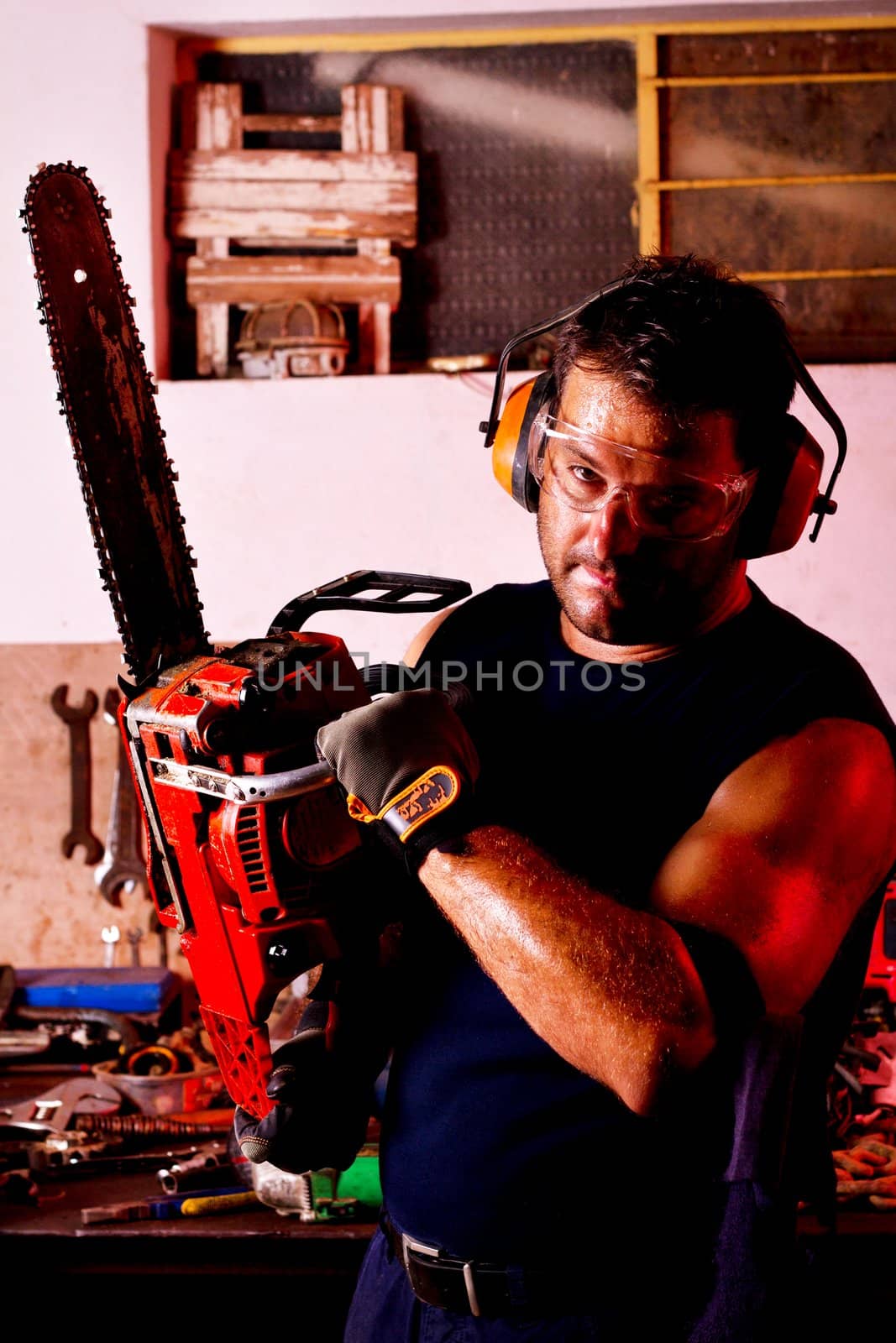 View of a garage mechanic man holding a chainsaw.