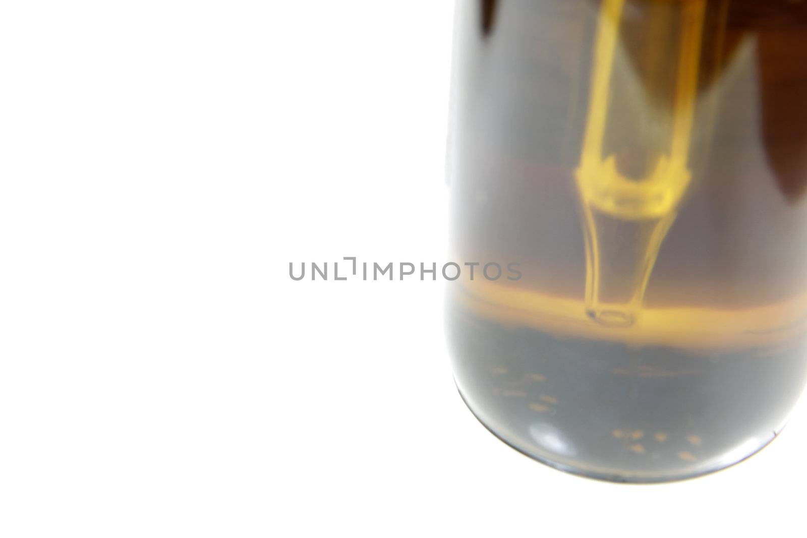 An extreme close-up of the dropper in a bottle containing naturopathic medicine, isolated on a white background.

