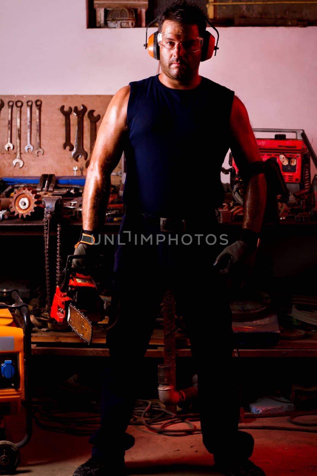 View of a garage mechanic man holding a chainsaw.