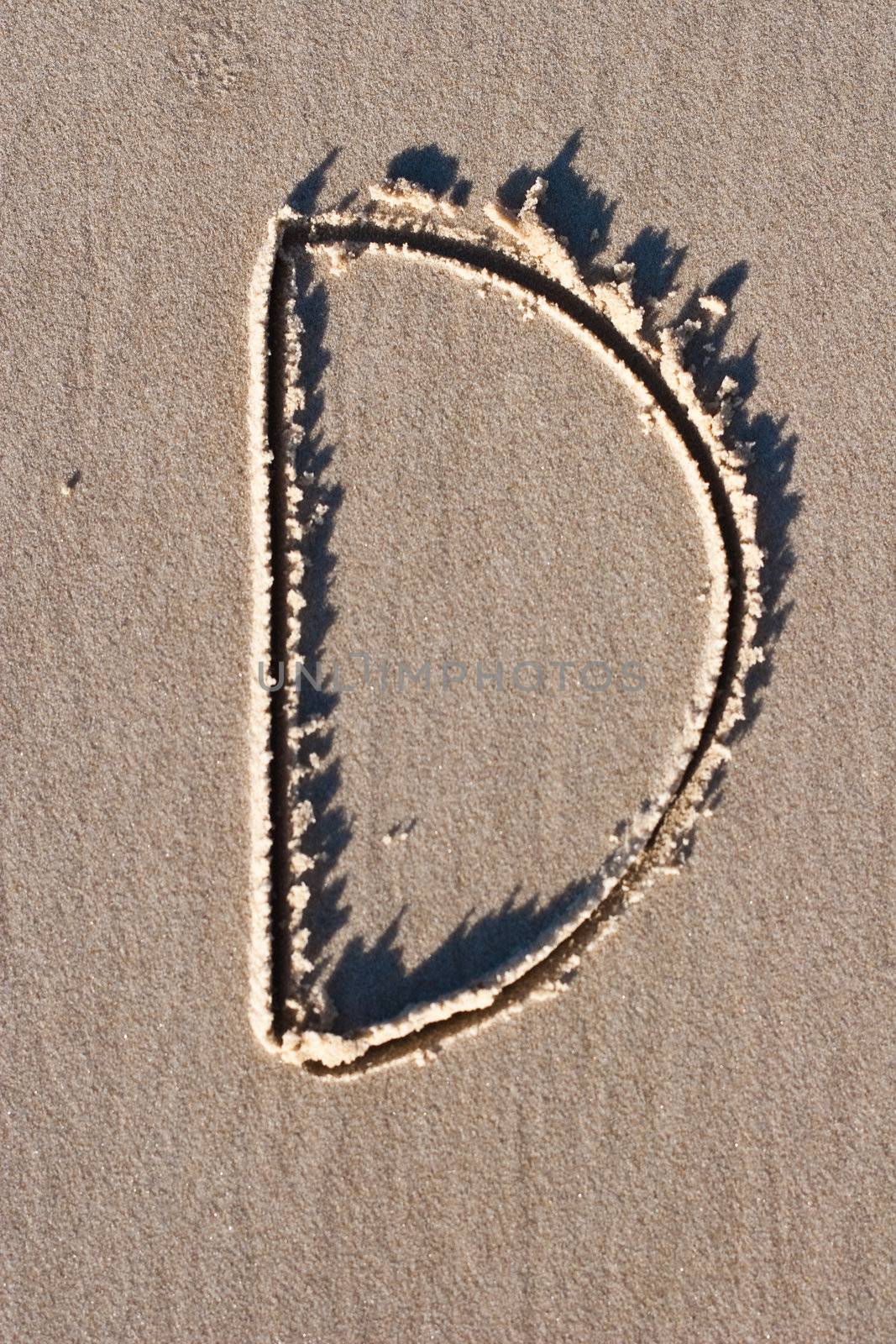 Letter D drawn in the sand. 