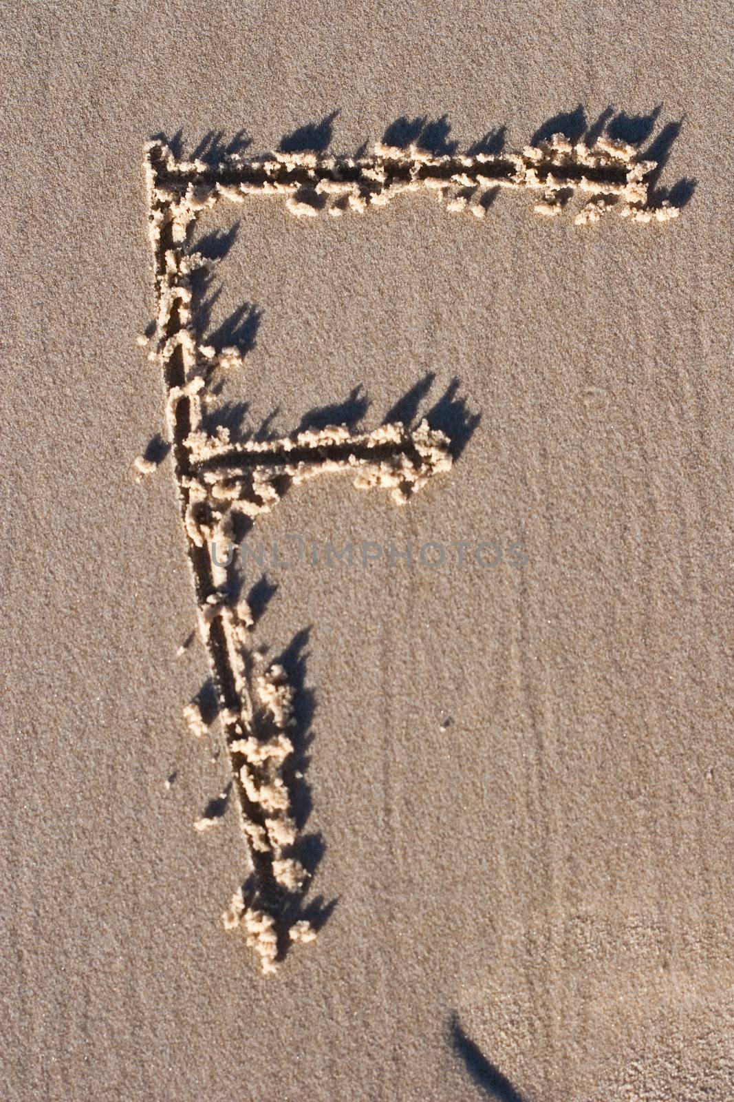 Letter F Drawn in the sand.