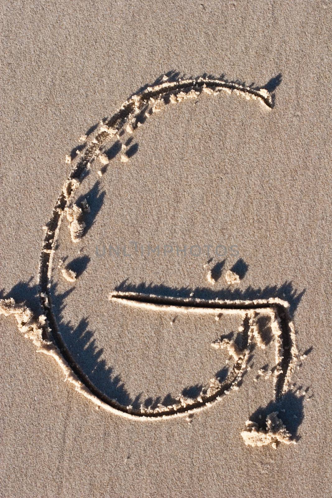 Letter G drawn in the sand.