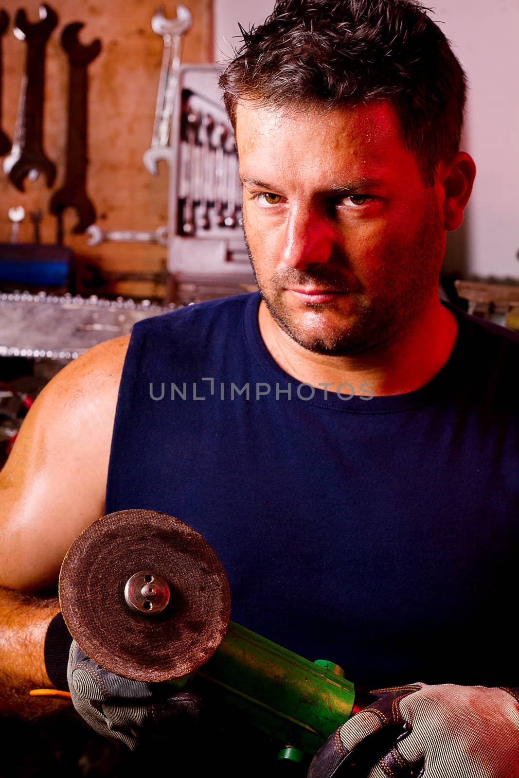 View of a garage mechanic man holding a power saw.