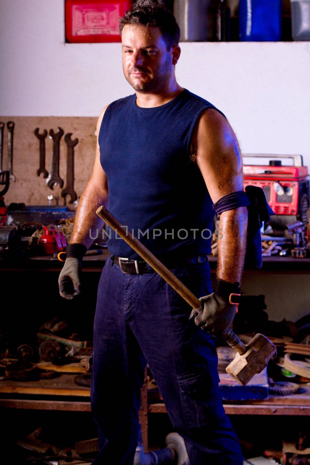 View of a garage mechanic man holding a big hammer.