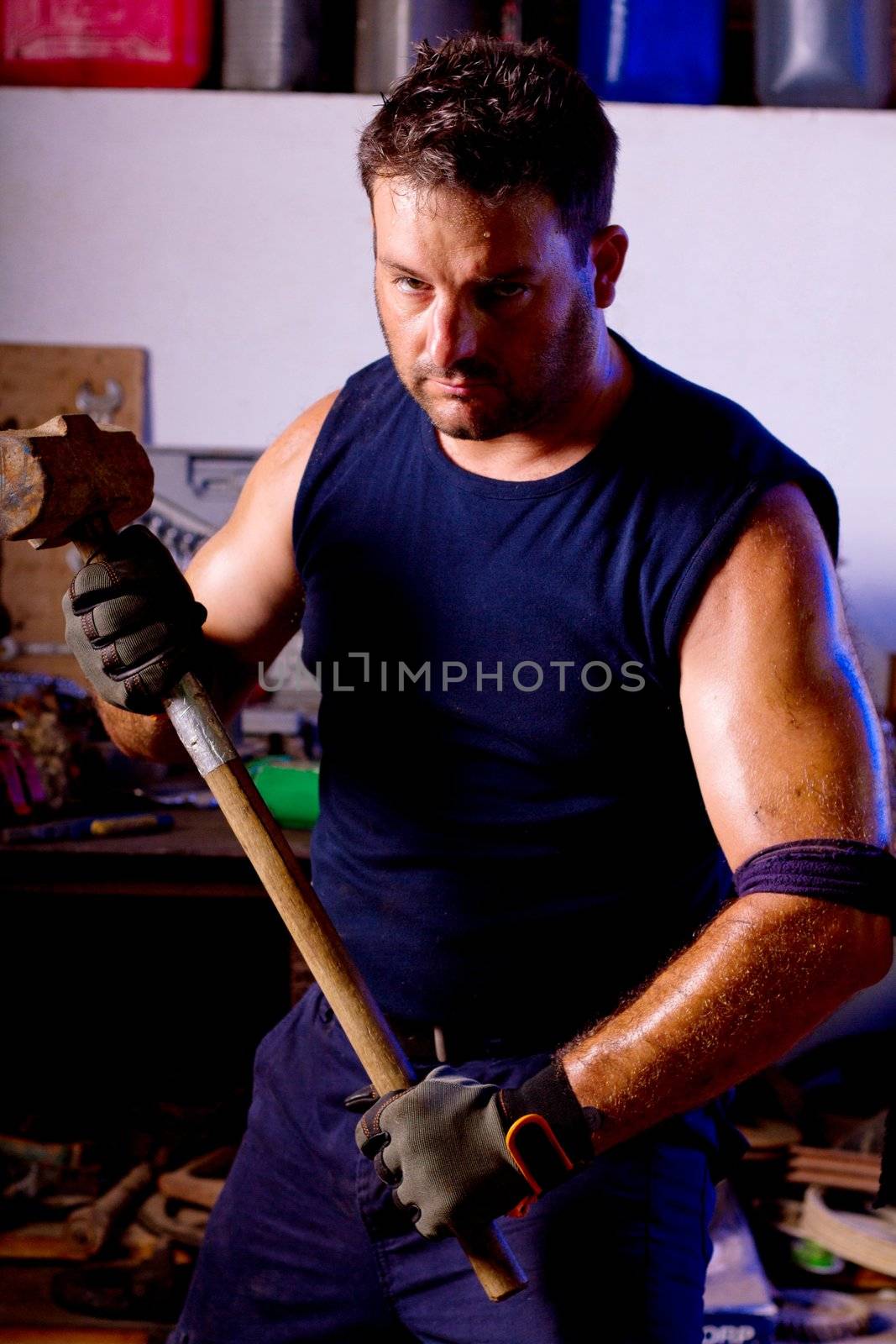 View of a garage mechanic man holding a big hammer.