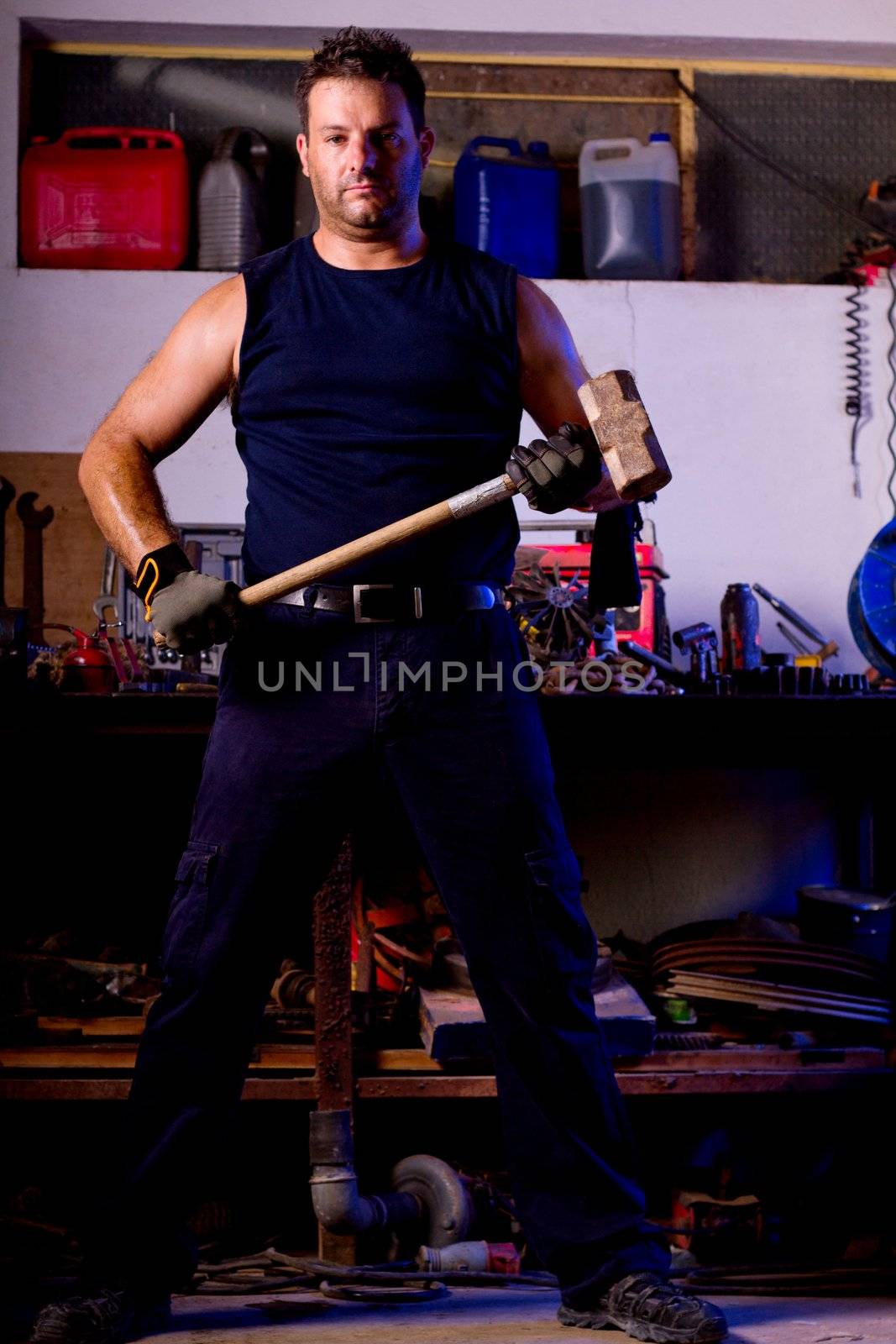 View of a garage mechanic man holding a big hammer.