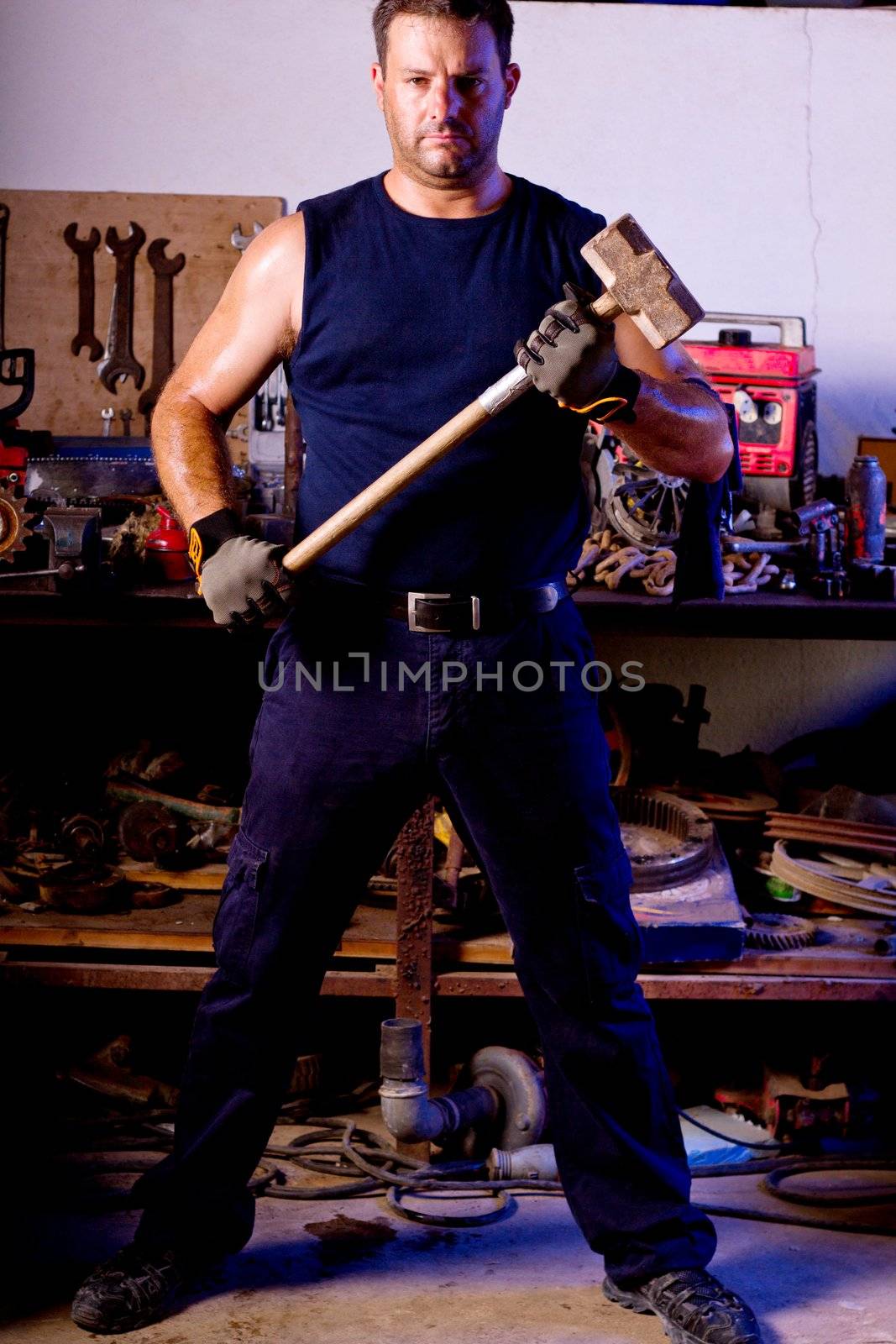 View of a garage mechanic man holding a big hammer.