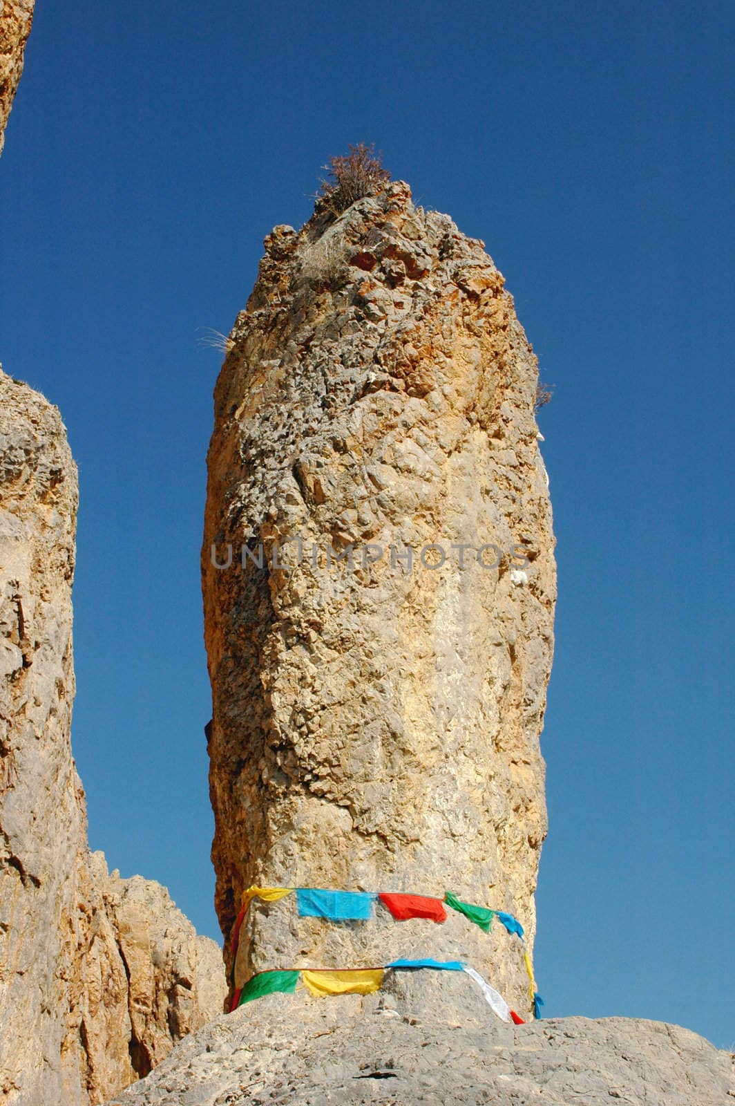 Big rock surrounded by colorful prayer flags in Tibet