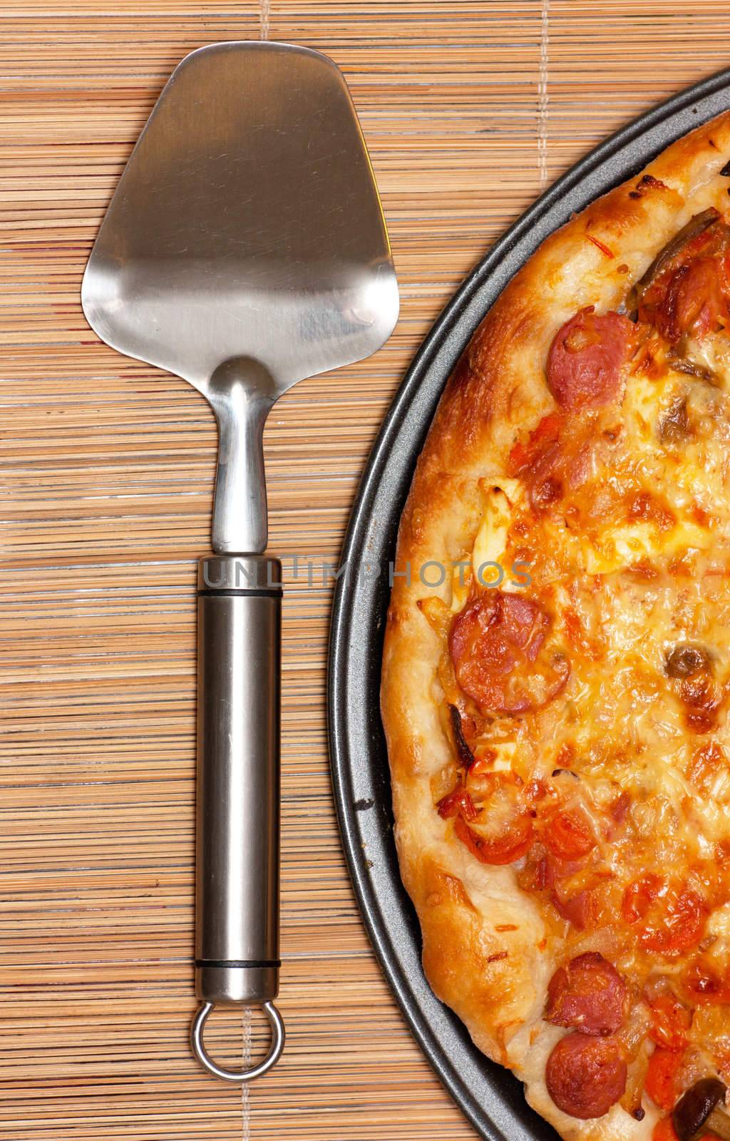 Pizza and spatula on a straw background