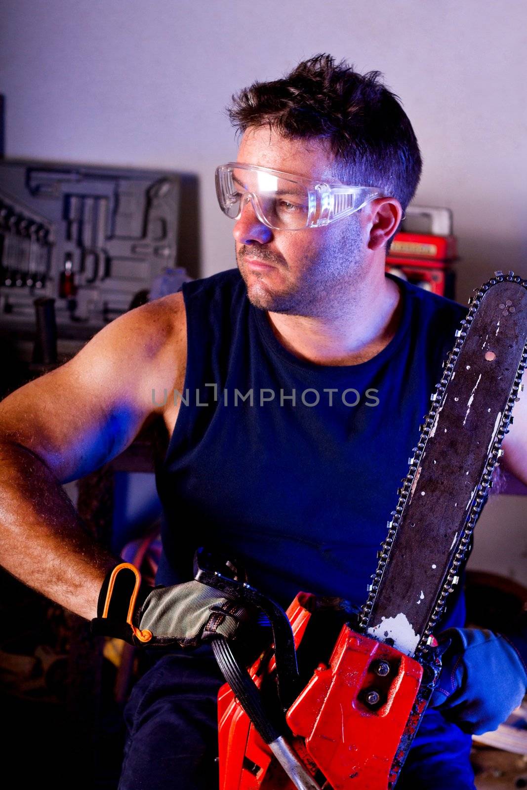 View of a garage mechanic man holding a chainsaw.