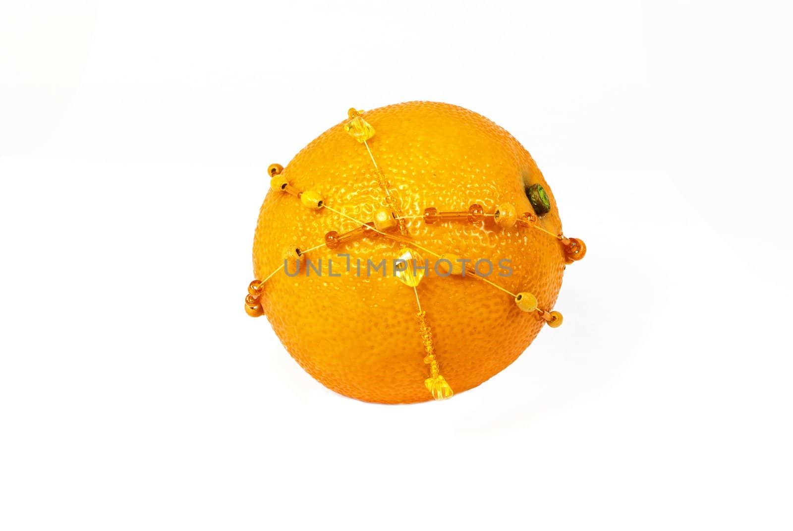 Single fresh orange decorated with amber bracelets