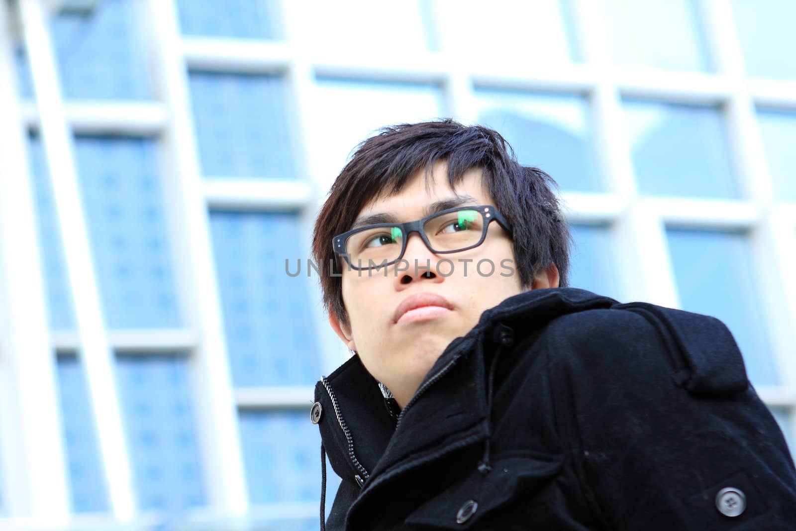 Image of pensive guy looking aside on the background of modern office building 