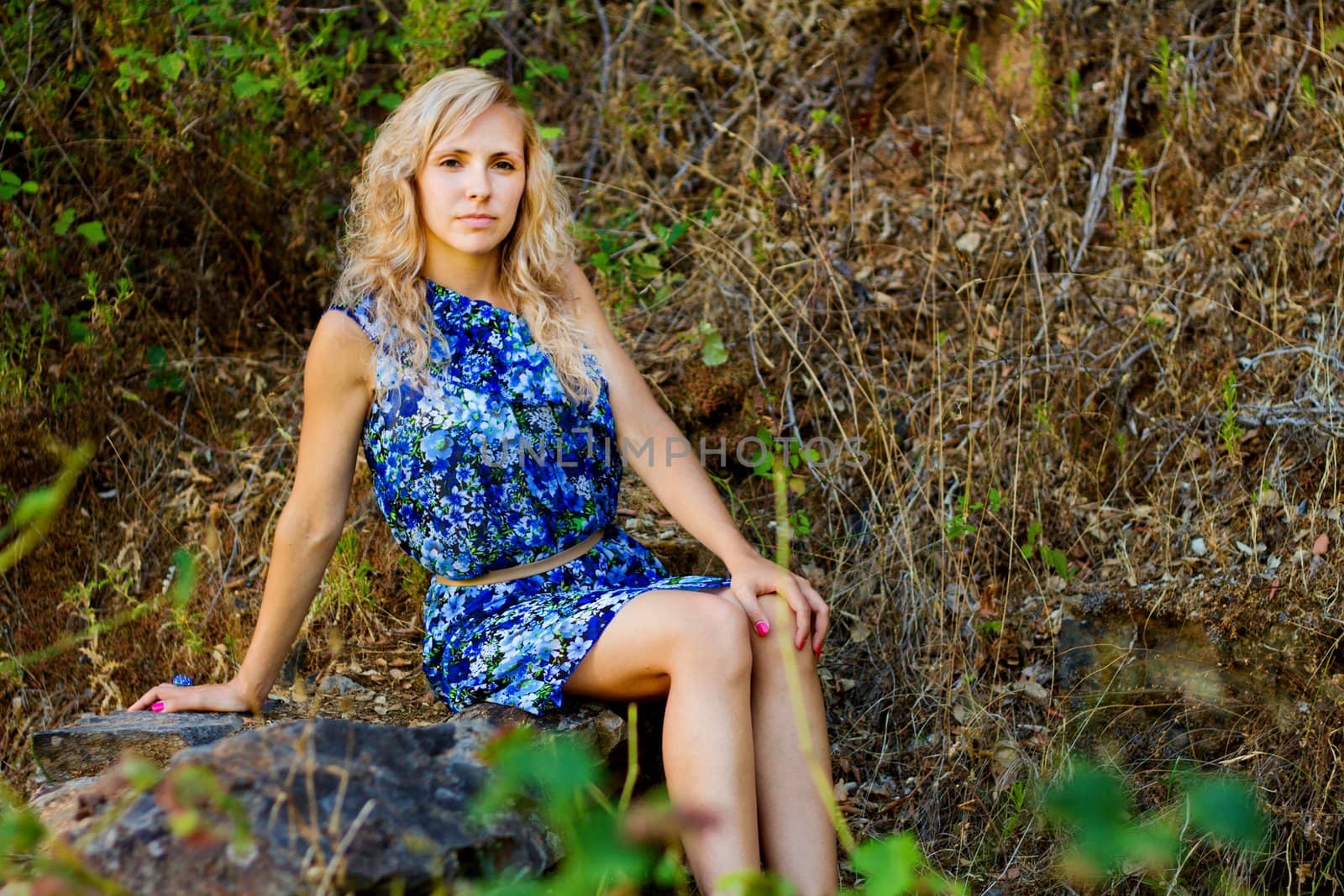 View of a beautiful young girl with a blue dress on the forest.