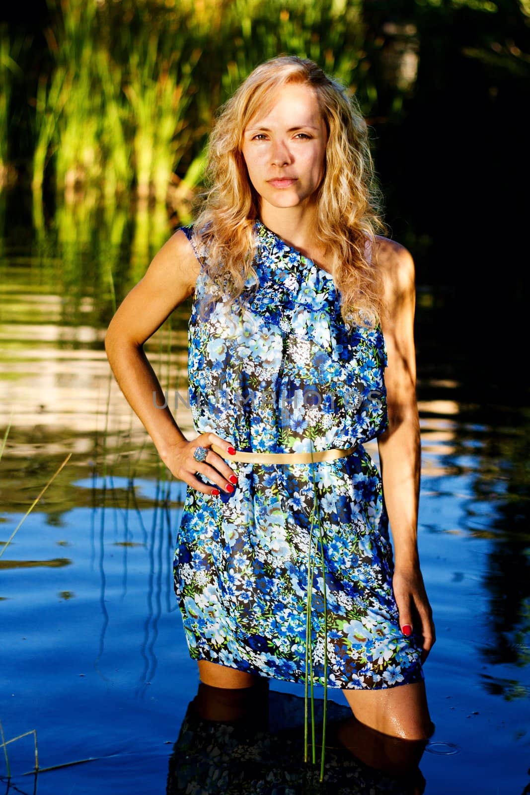 View of a beautiful young girl with a blue dress on the stream of a river.