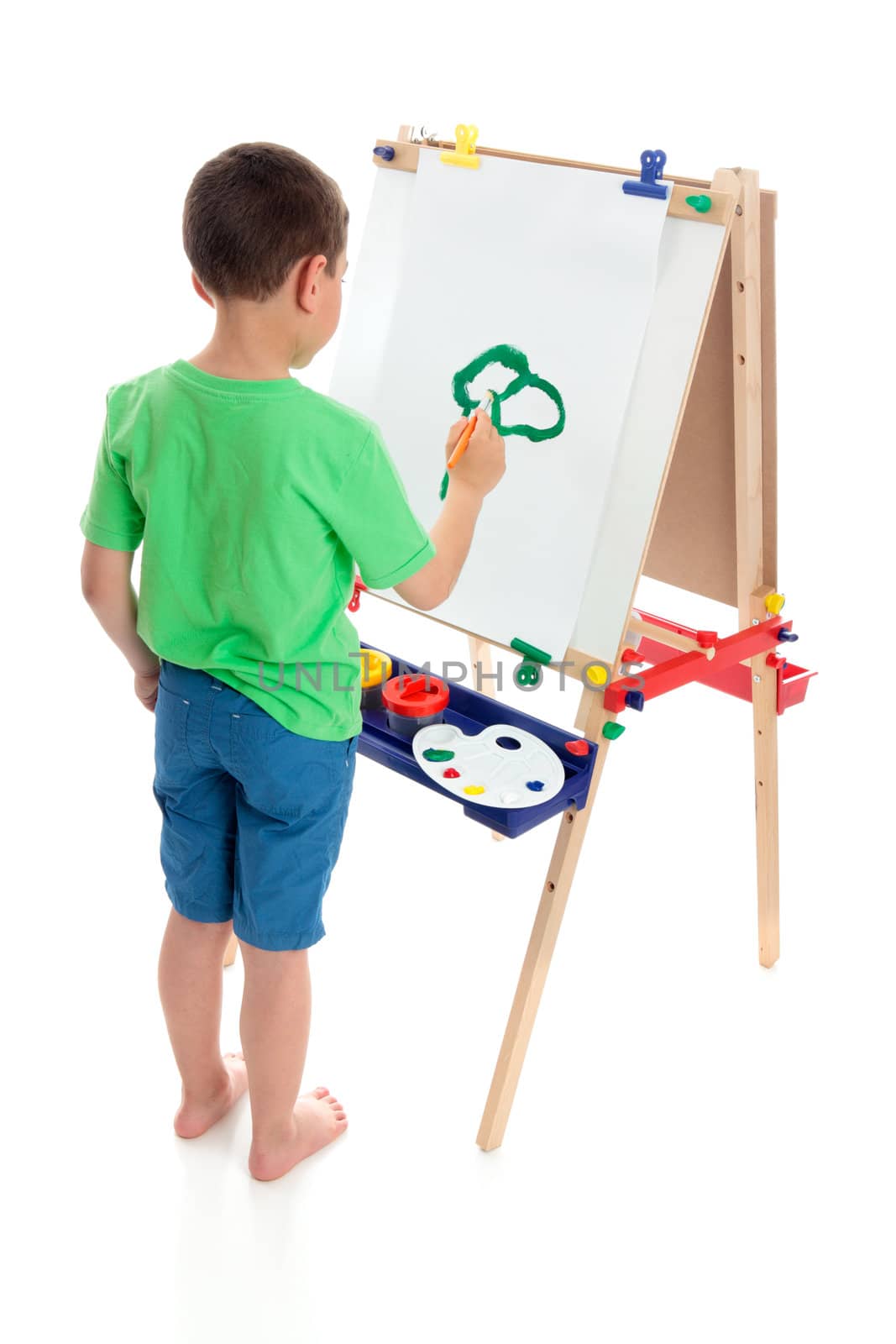 A young boy painting a picture on an art easel.  White background.