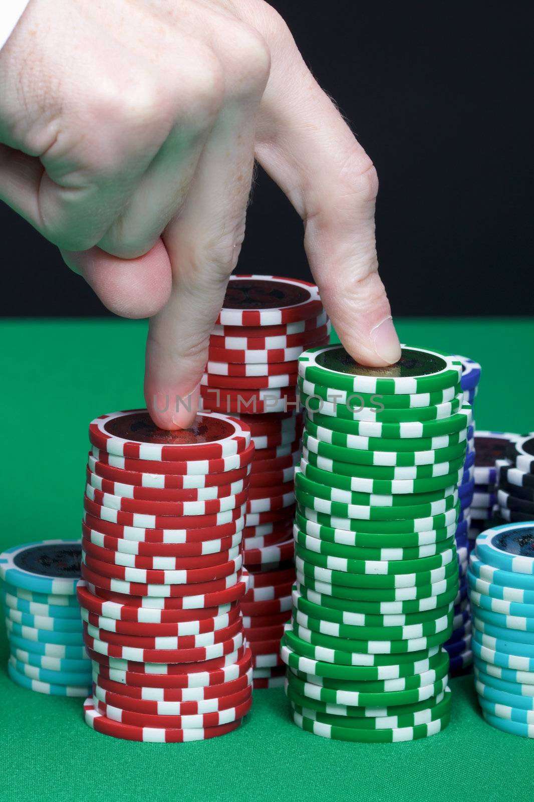 Men's fingers are marching up the pile of playing chips
