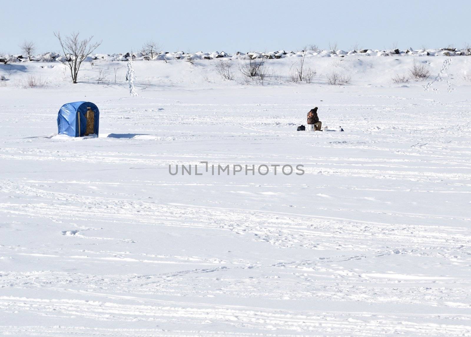 An ice fisherman on a frozen lake.