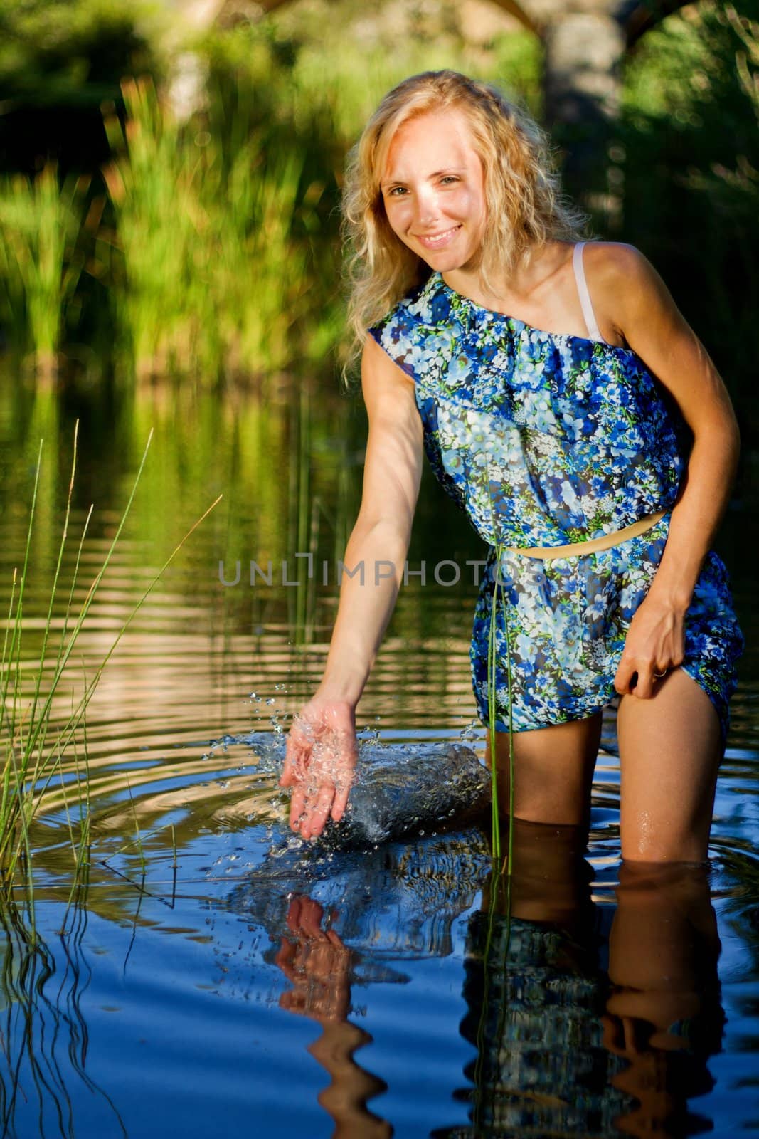 View of a beautiful young girl with a blue dress on the stream of a river.