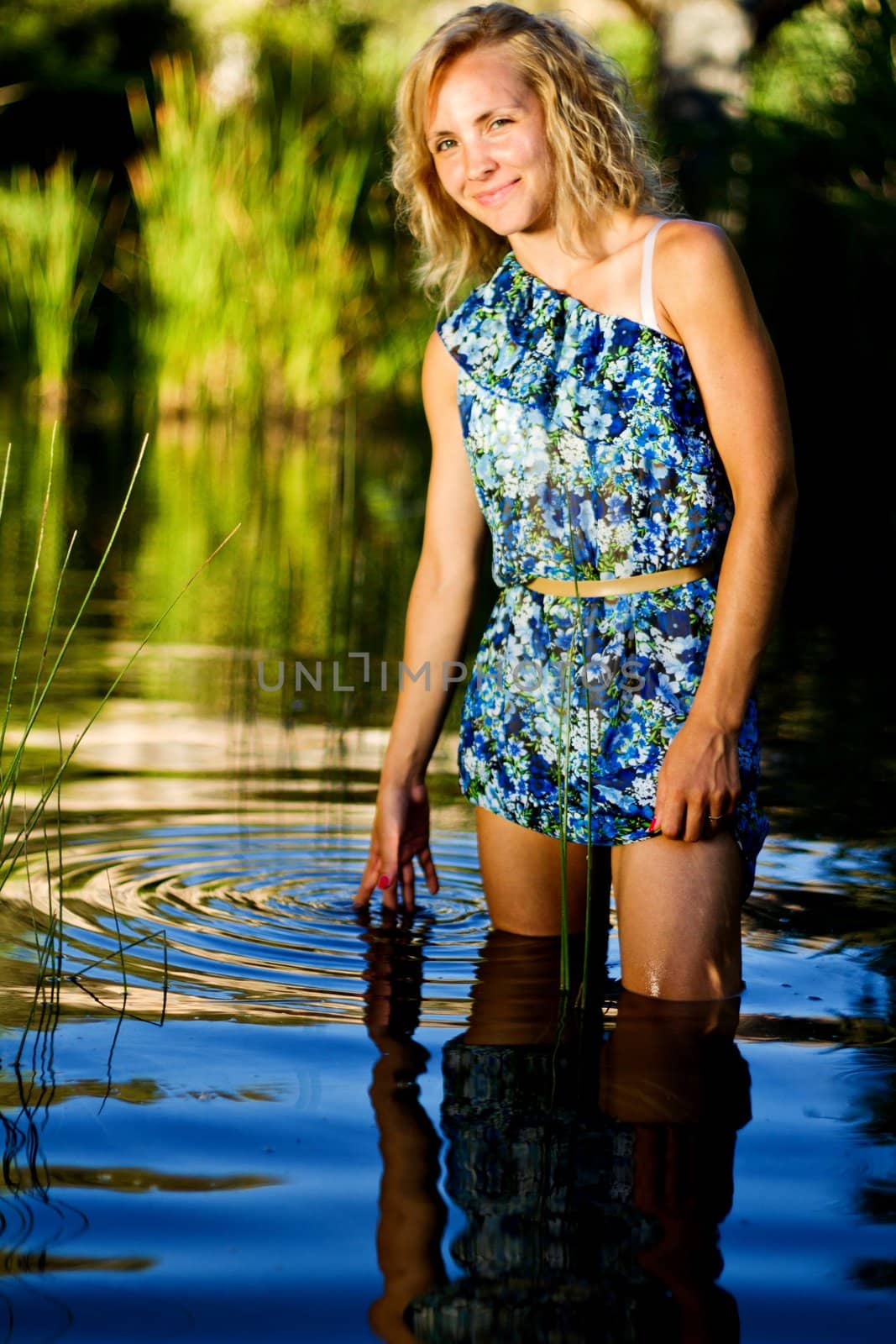 View of a beautiful young girl with a blue dress on the stream of a river.