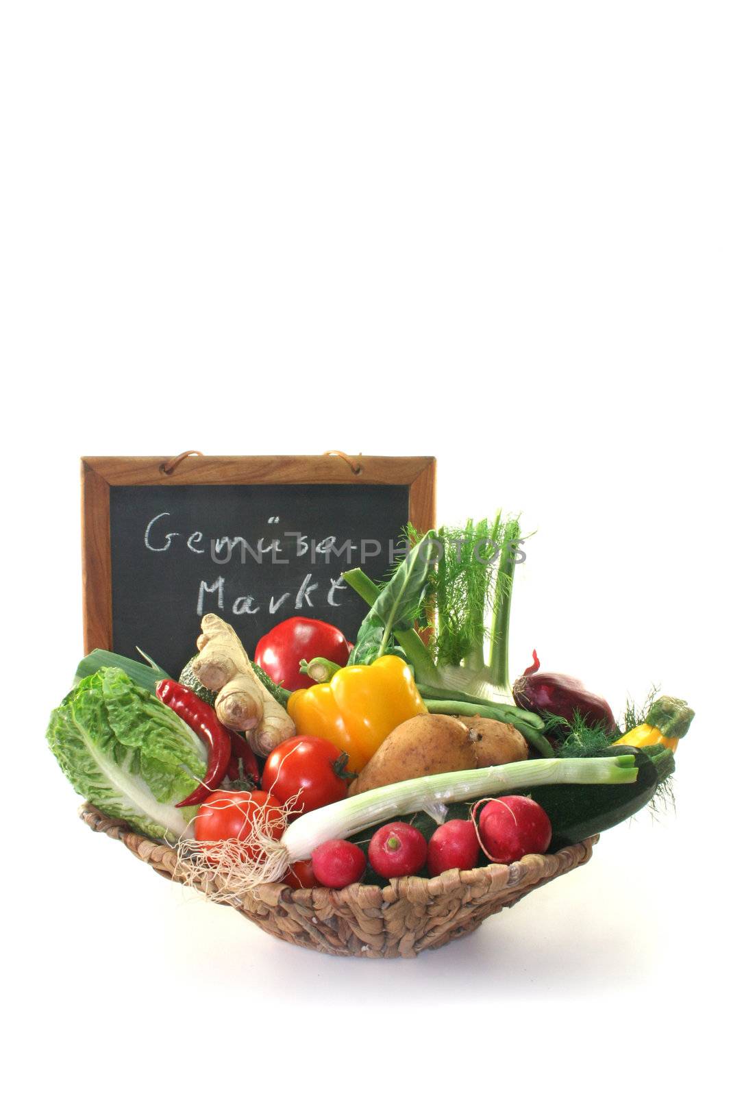 Colorful mix of many different fresh vegetables in a basket with a board