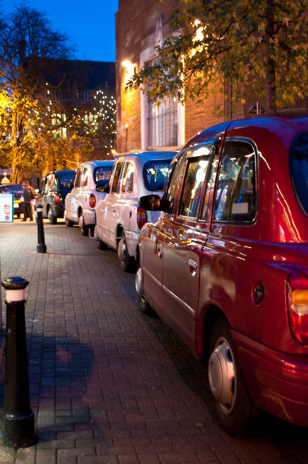 Low level evening shot capturing waiting British taxis in city setting.