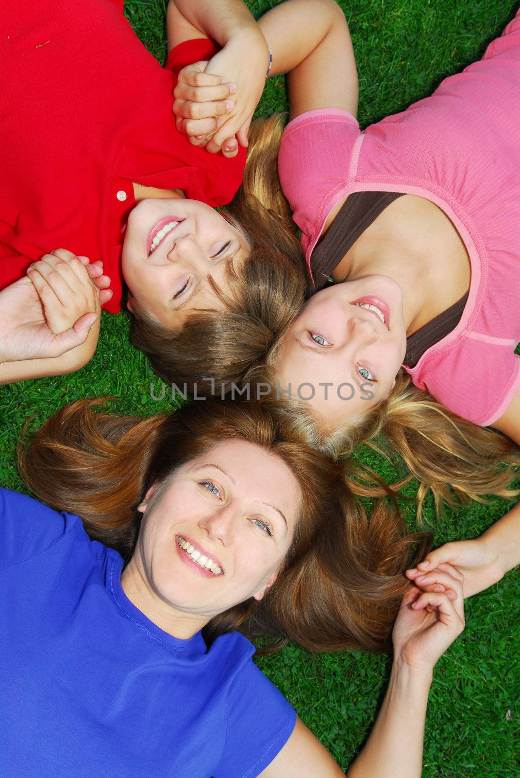 Family of happy mother and children relaxing on green grass