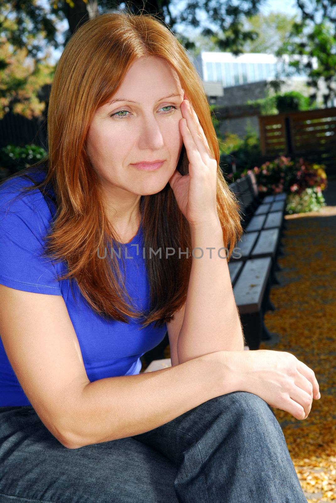 Mature woman looking sad and stressed sitting on a park bench