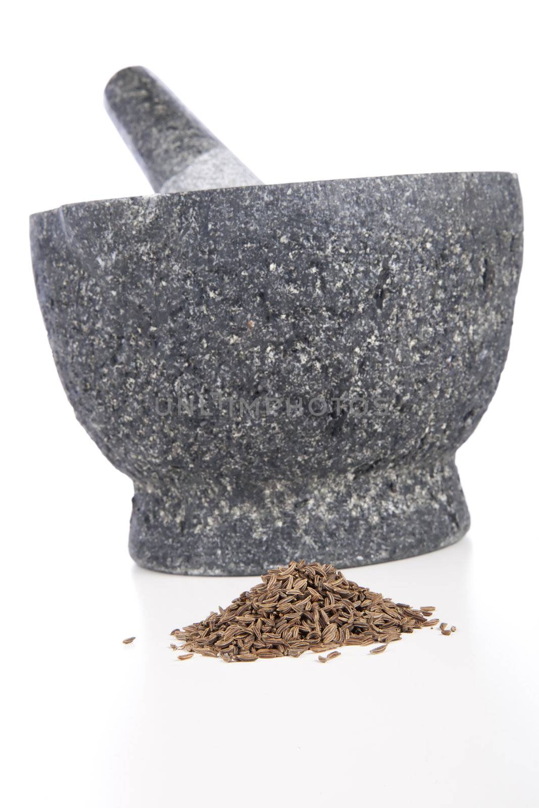 Granite mortar and pestle with fennel seeds on white background.