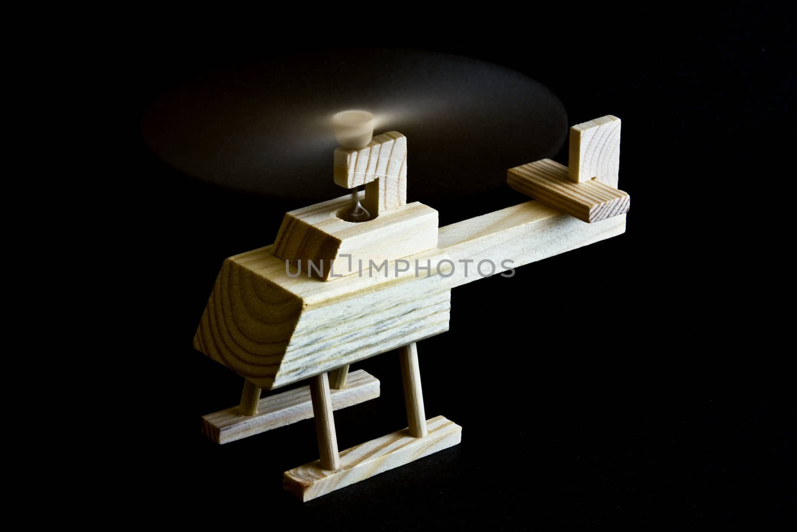 Wooden toy helicopter with spinning propeller on black background