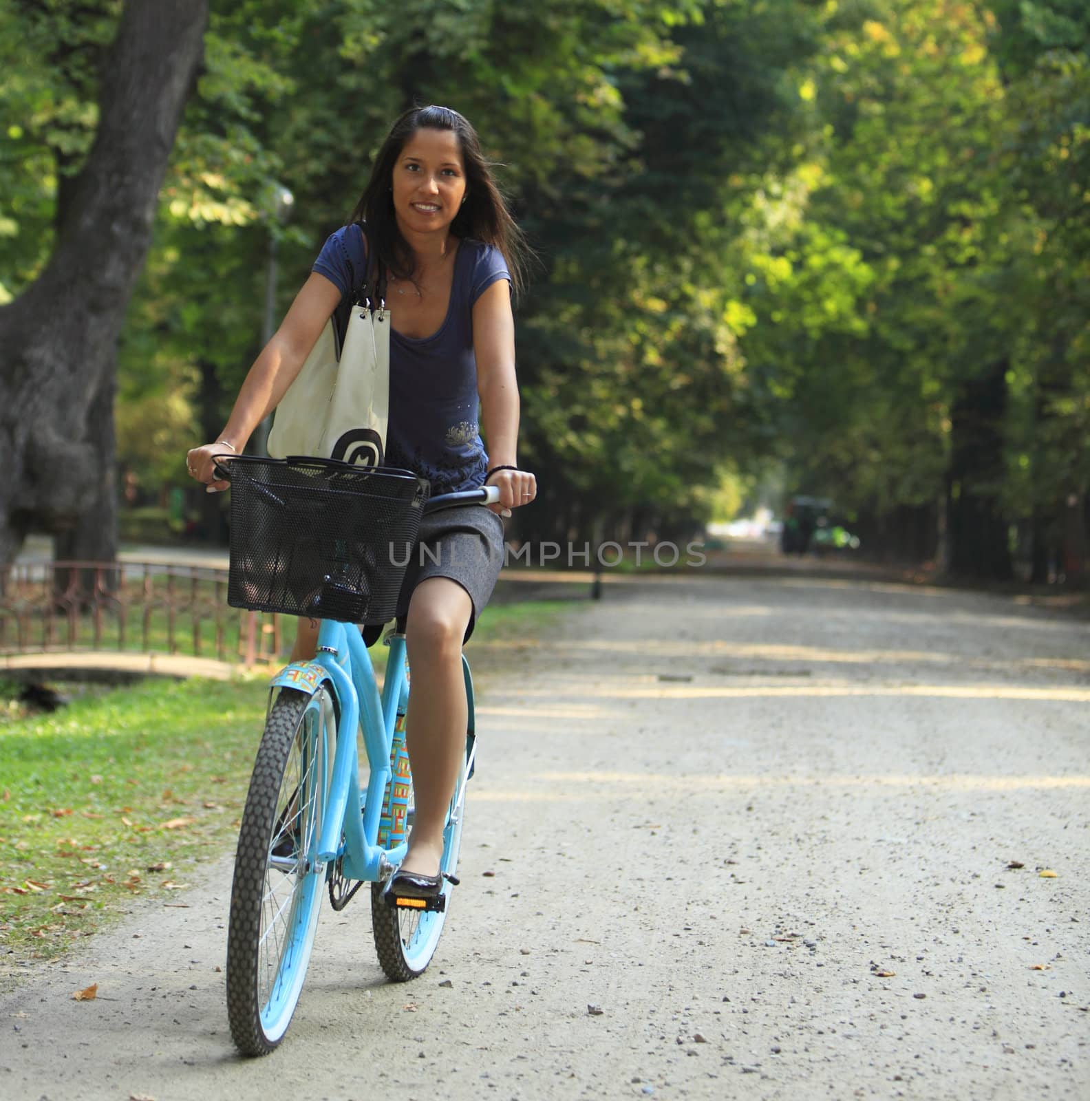 Young woman riding a bicycle in a park alley.