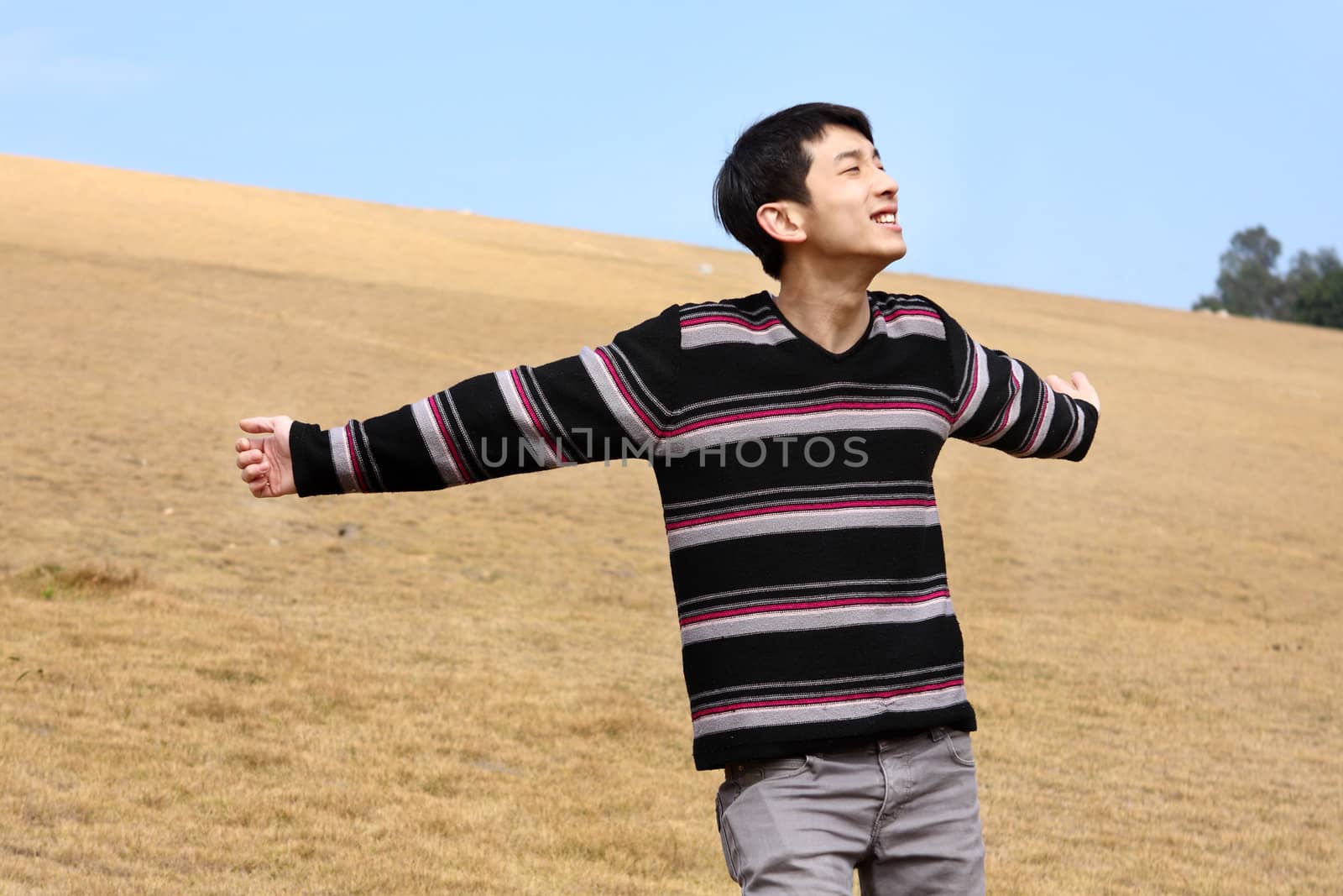 Carefree man standing in golden grass field being happy enjoying by cozyta
