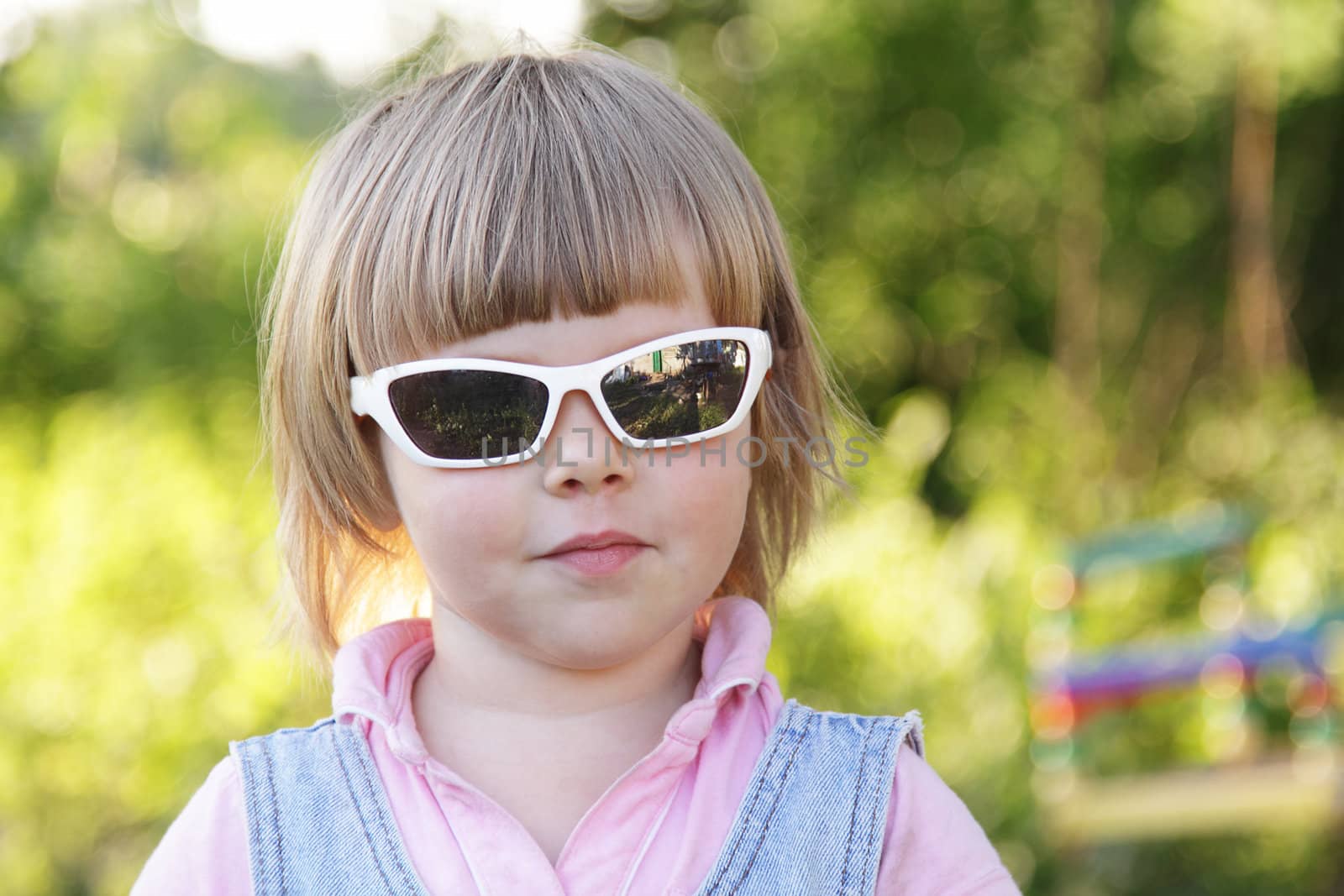 Cute little girl with sunglasses in the garden