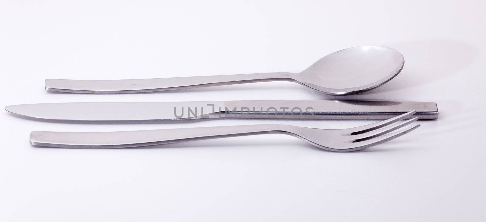 Knive fork and spoon from modern stainless steel design isolated against white and reflecting white light