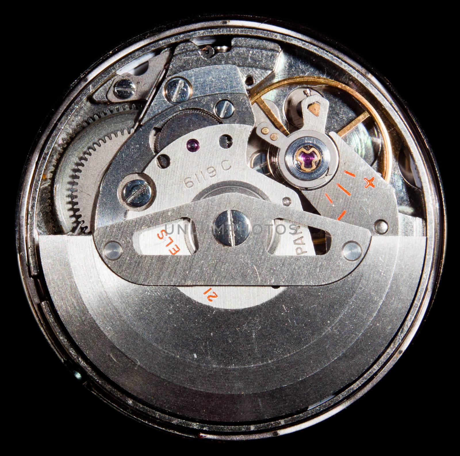 Macro image of the workings of an automatic wristwatch with cogs and polished stainless steel and ruby jewel