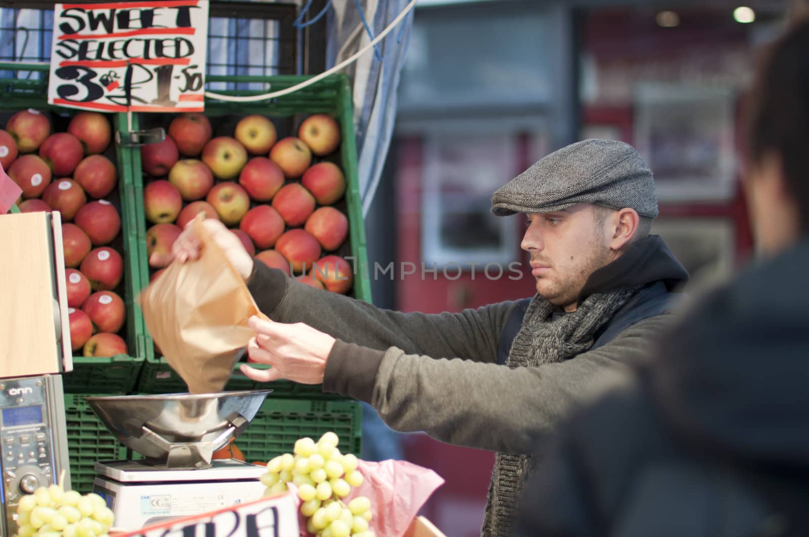 LONDON - FEBRUARY 04: Street vendor wraps up fruits for his customer in Oxford Street, where he competes with large supermarket chains. February 04, 2011 in London, England.