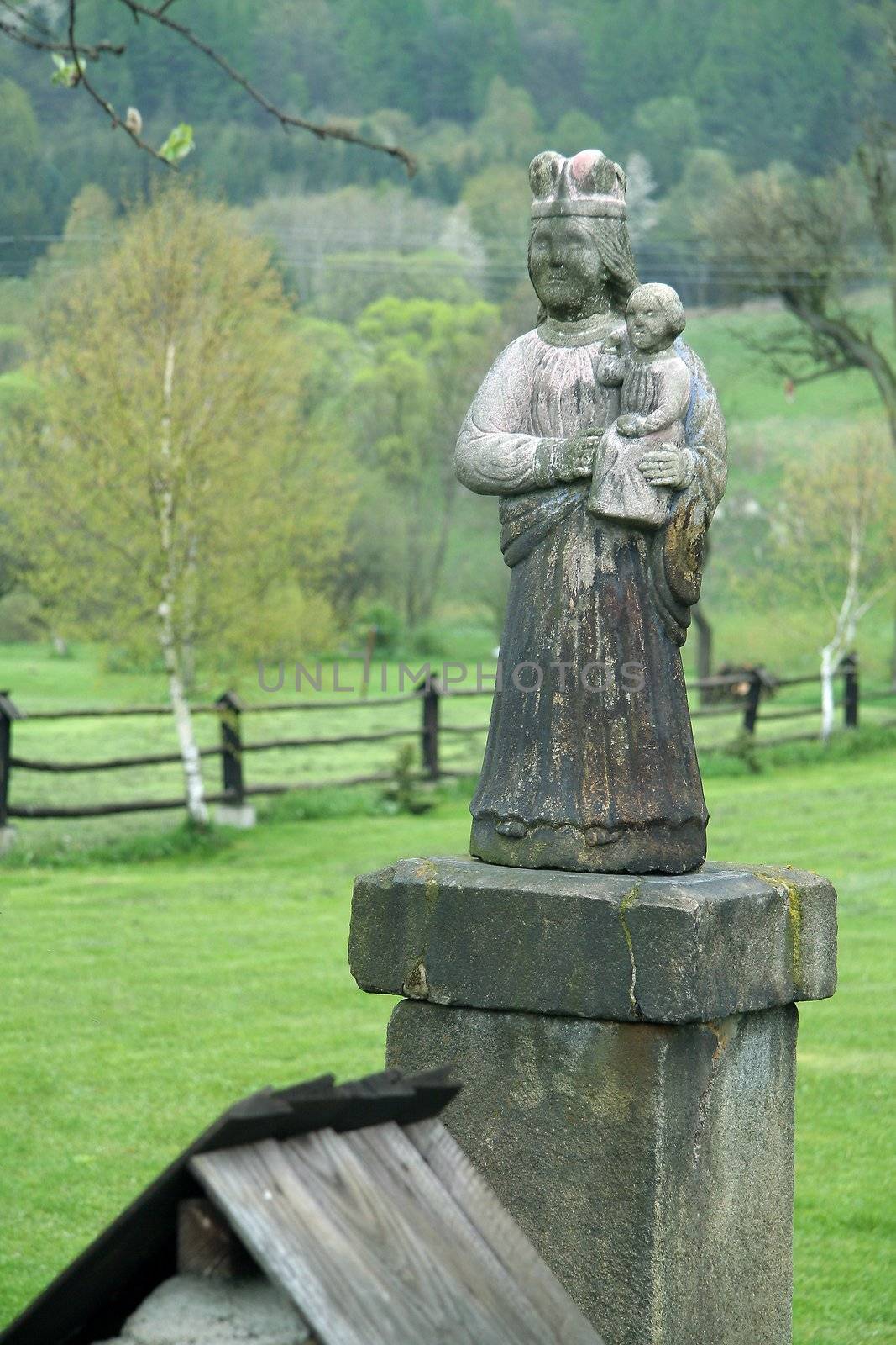 old concrete religious statue, rural landscape in background