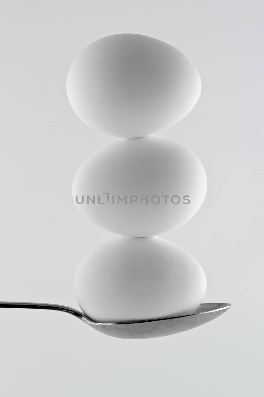 Three white eggs balancing on a spoon