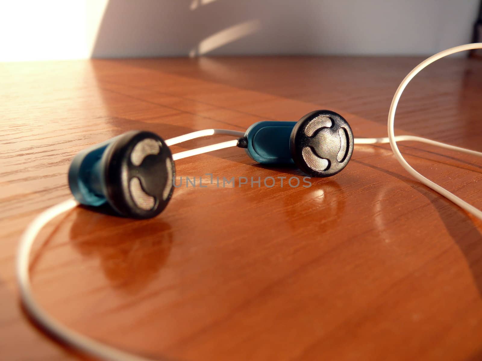 Blue earphones with wires in the brown table by Stoyanov
