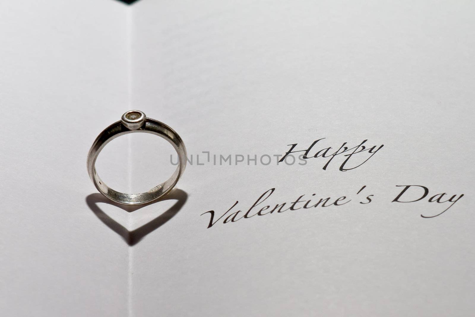 Ring casting heart shadow in book with the sentence "Happy Valentine's Day"