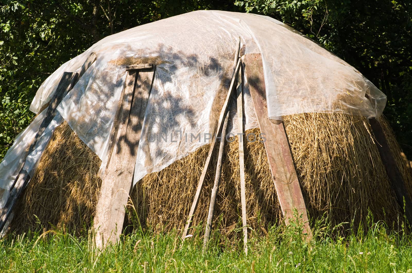 a large stack of hay covered with cellulosic packing material