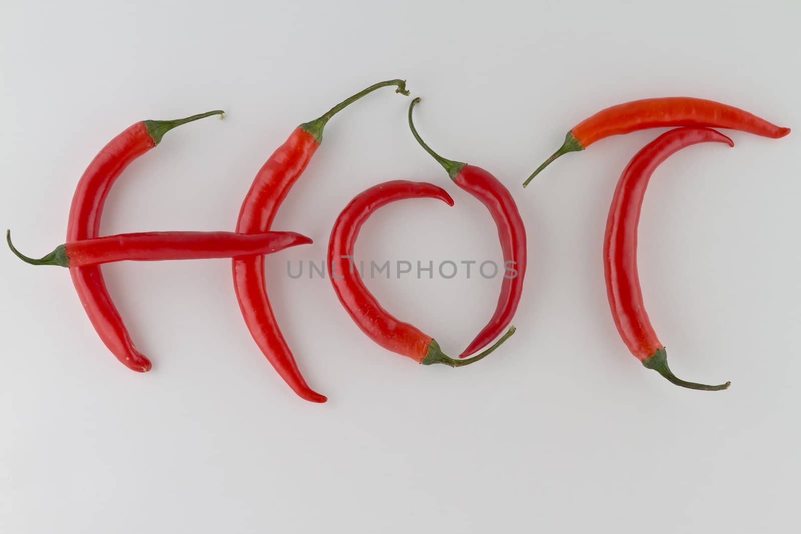 Red hot chili peppers arranged as the word HOT on white background