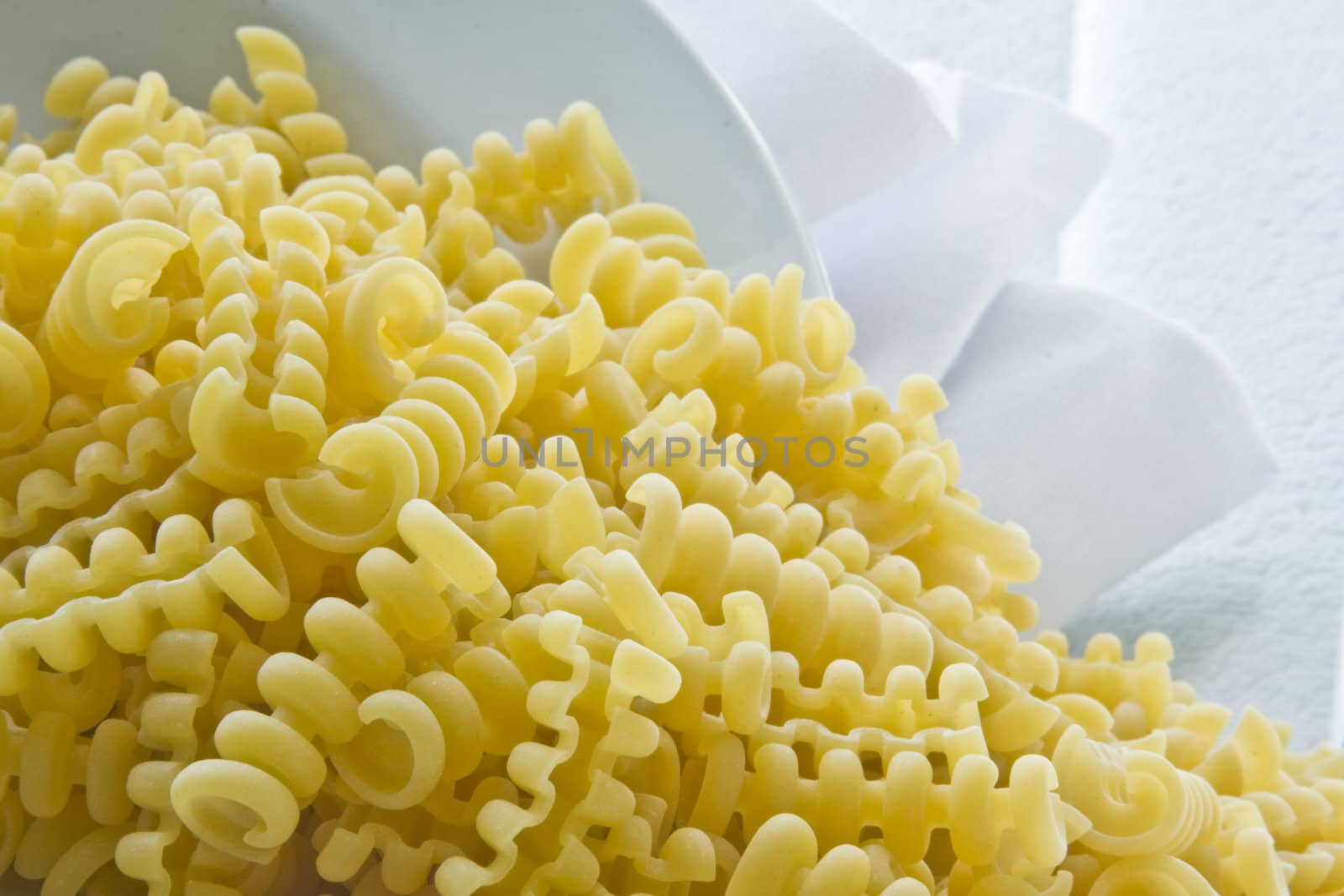 Uncooked riccioli pasta with with bowl and napkin