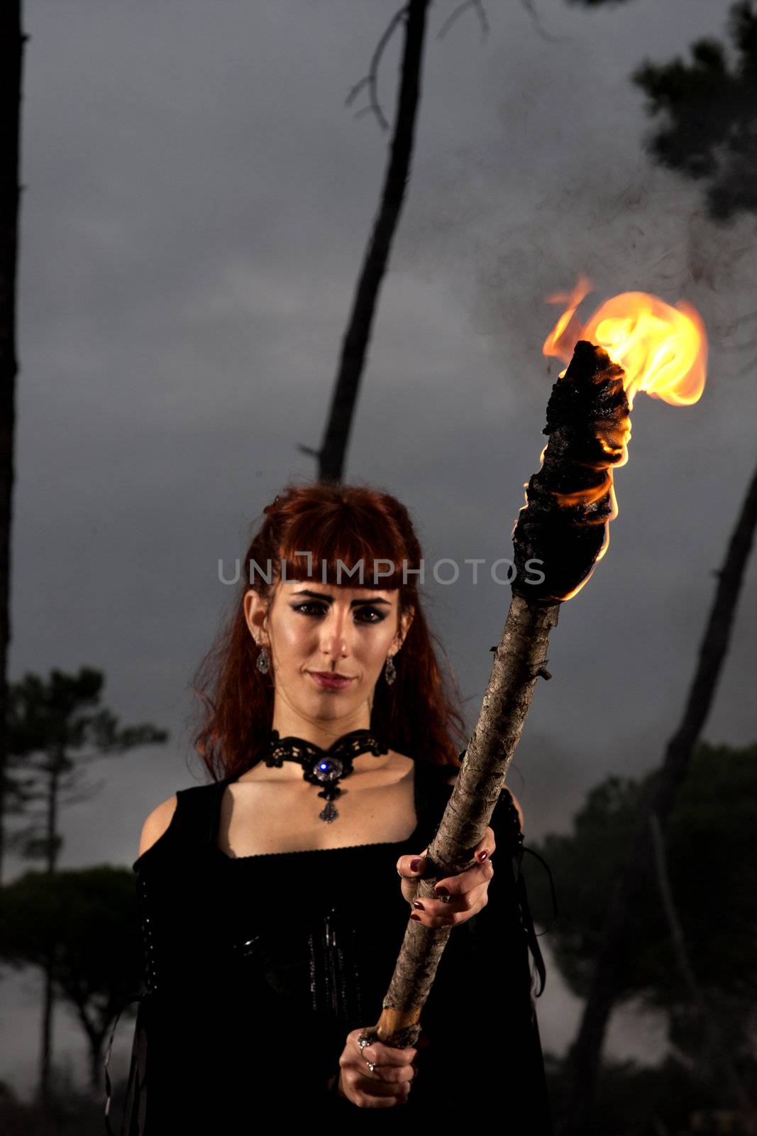 View of a dark clothed woman with a torch on her hands.