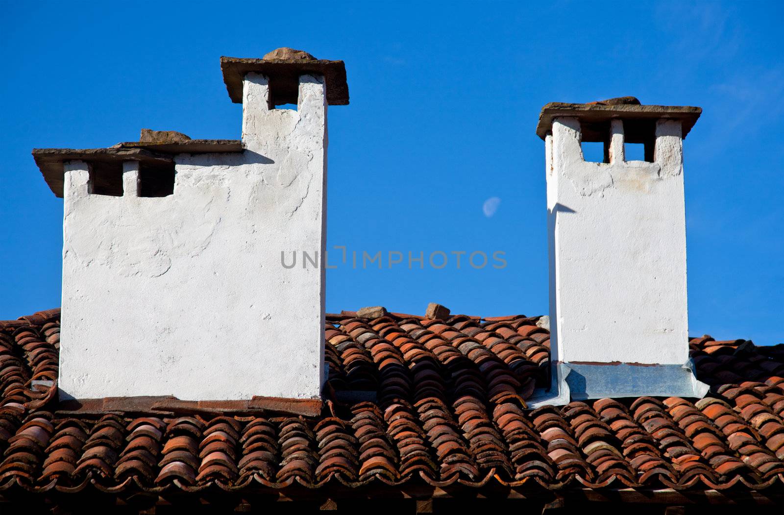 Tiled house roof with two stone chimneys