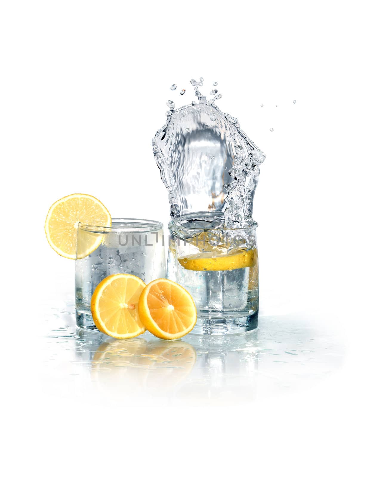 Two glasses of splashing water with ice and lemon. Isolated on white with clipping path