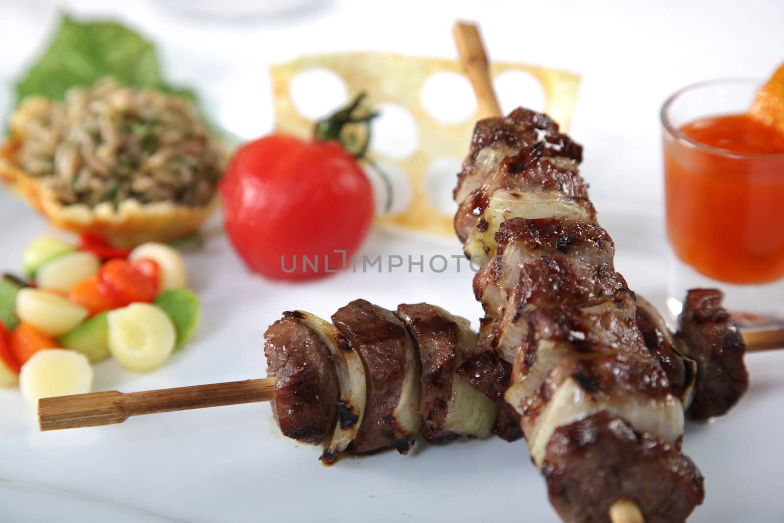 Meat skewers on a dish with tomato and vegetables