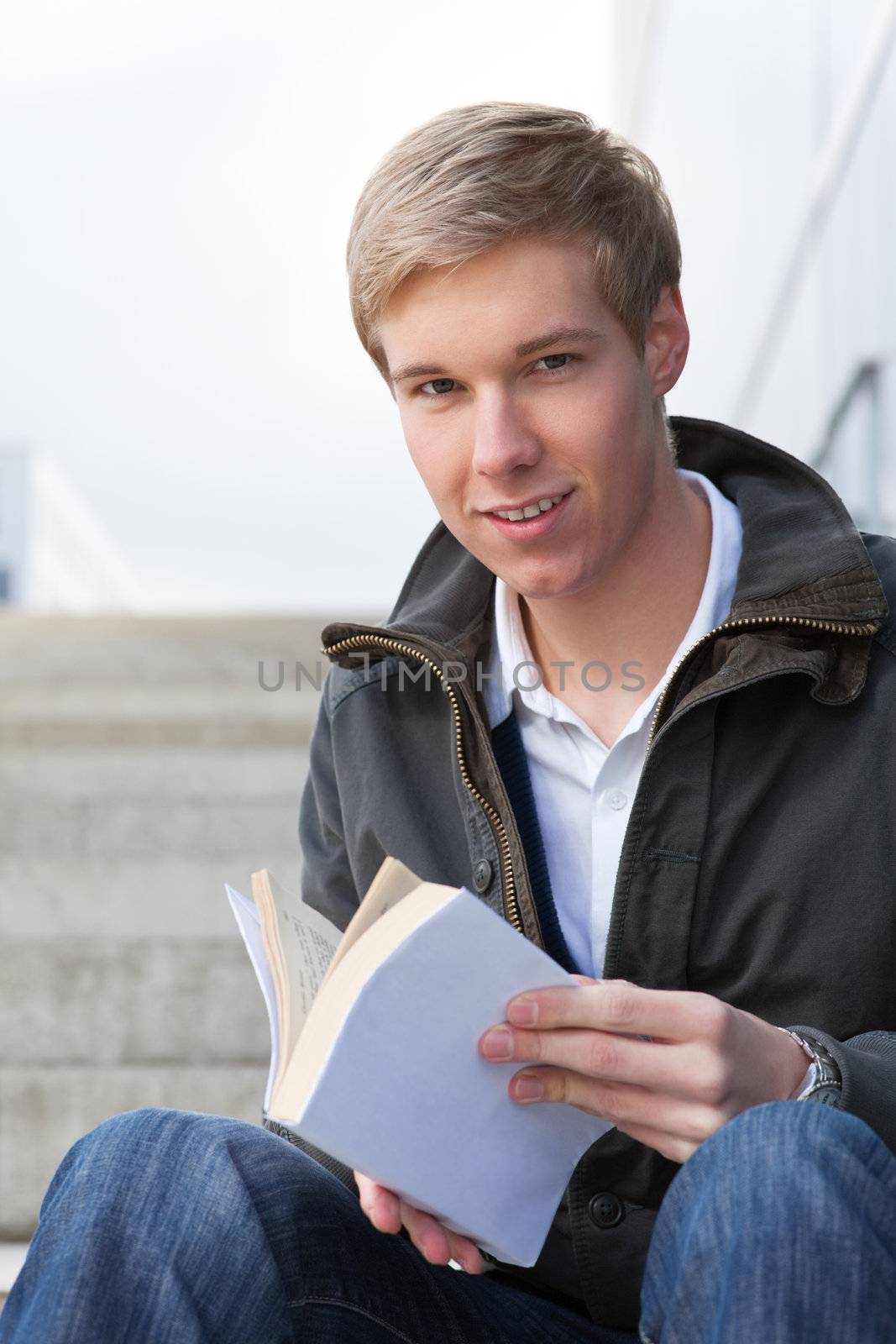 Young cheerful handsome guy holding a book with blank cover